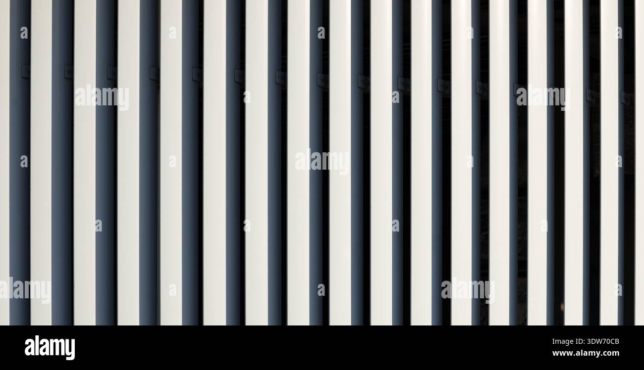Nahaufnahme einer Gebäudefassade mit sich wiederholenden vertikalen Elementen in kontrastierenden Farben, die eine zeitgenössische Design-Ästhetik zeigen Stockfoto