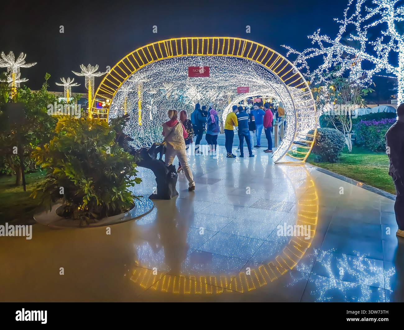 Sharm El Sheikh, Ägypten - 18. Januar 2020: Die Menschen fotografieren nachts im leuchtenden Tunnel auf dem Soho-Platz in Sharm El Sheikh. Touristen ruhen sich aus - Smartphone-aufgenommenes Stockfoto