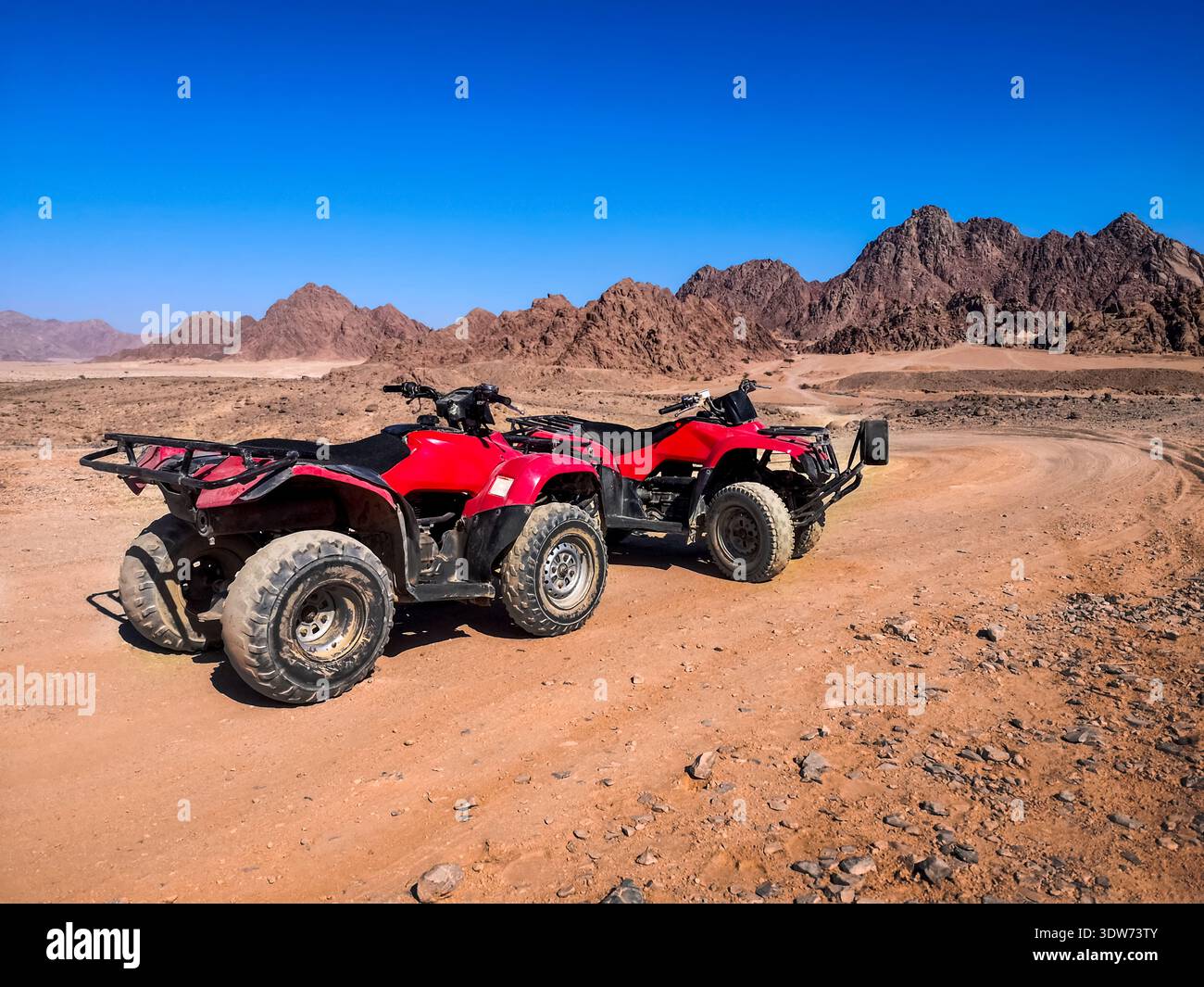Zwei rote Quads stehen in der Nähe der Berge in der Wüste Süd-Sinai bei Sharm El Sheikh (Ägypten). ATV Safari Konzept, aktive Freizeit für Touristen - Smartphone-aufgenommenes Stockfoto