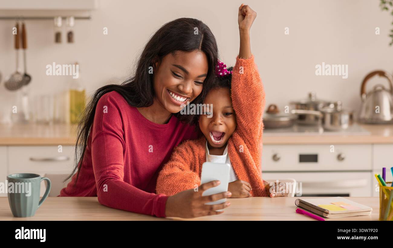 Lächelnde Mutter und Tochter teilen sich einen freudigen Moment, während sie ein Selfie drinnen machen Stockfoto