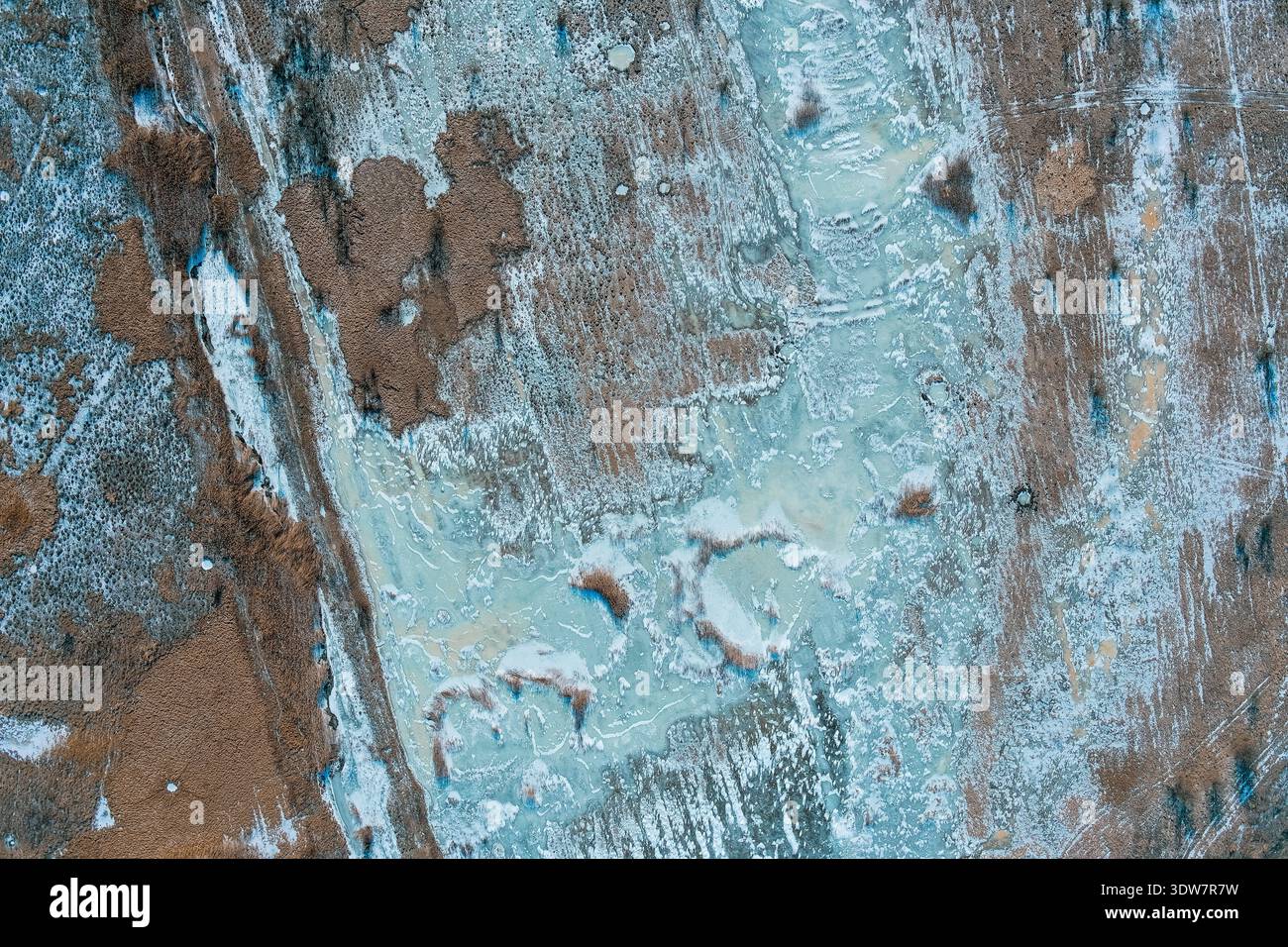 Bizarre kreisförmige Eisfelder verstreut über trockene Winterfeuchtgebiete und braune Erdfelder. Drohnenfotografie aus der Luft. Die ungewöhnlichen Gefriermuster bieten eine surreal strukturierte Umgebung. Stockfoto
