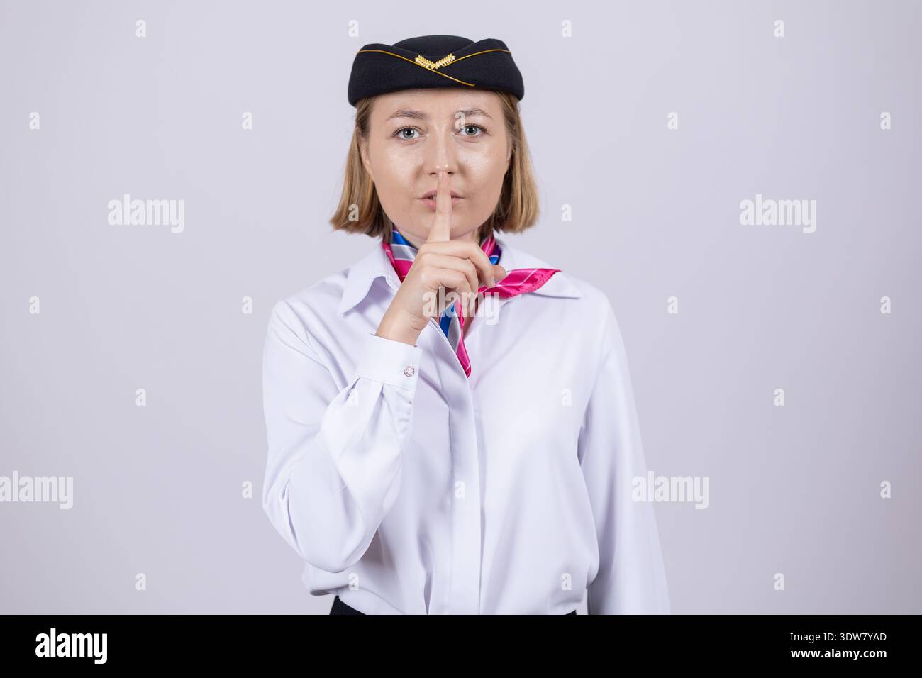 Weibliche Pilotin in Uniform mit schweigender Geste mit dem Finger Stockfoto