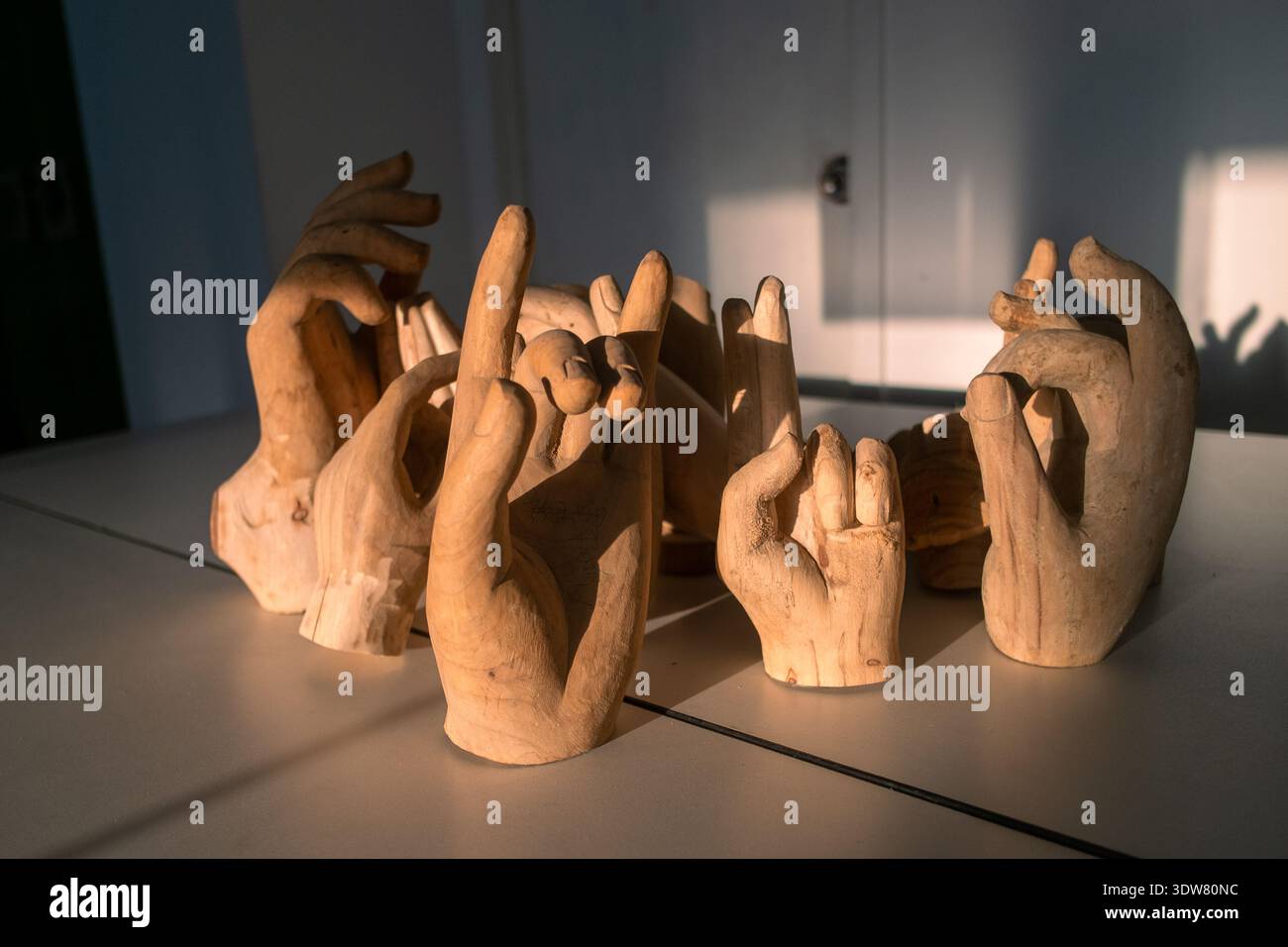 Ein horizontales Stillleben mit einer Gruppe geschnitzter Holzskulpturen in verschiedenen Gesten, angeordnet auf einem Tisch mit dramatischer Seitenbeleuchtung. Stockfoto