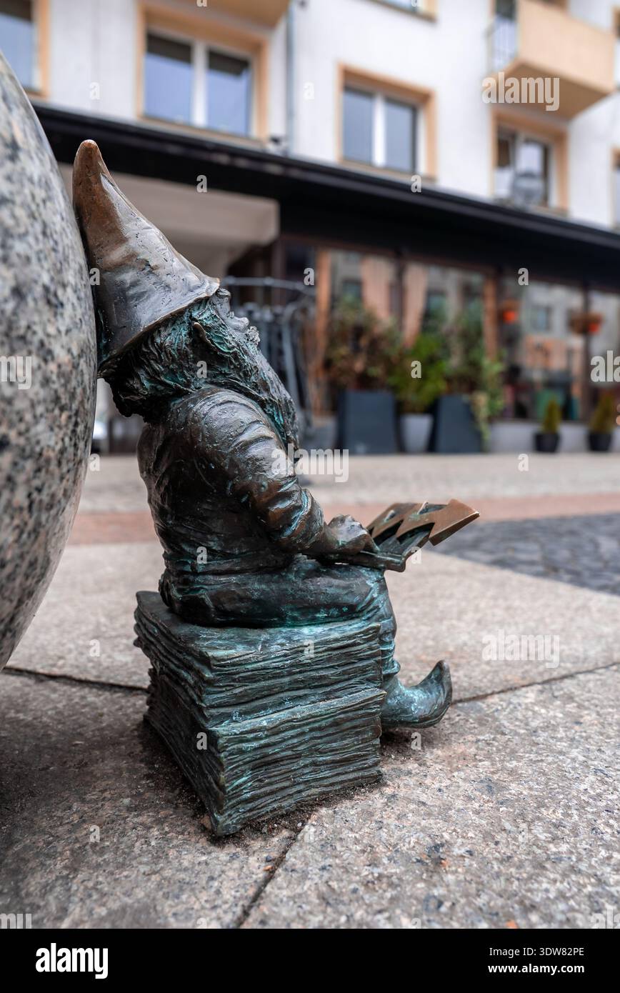 Breslauer Bronzedwerg auf Büchern mit Blitzsymbol durch Granitkugel Stockfoto