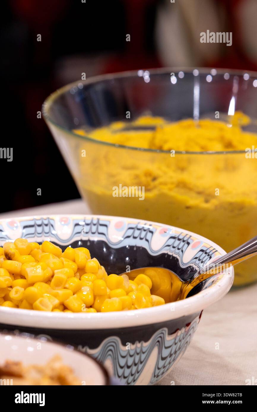 Schüssel mit süßem Mais mit Hummus im Hintergrund auf Küchentisch Stockfoto