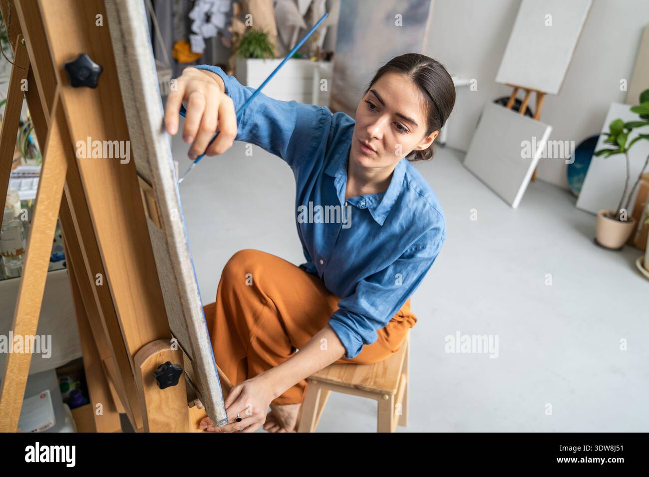 Konzentrierte talentierte Künstlerin malte Bilder auf Leinwand im Studio und schuf ein Meisterwerk. Stockfoto