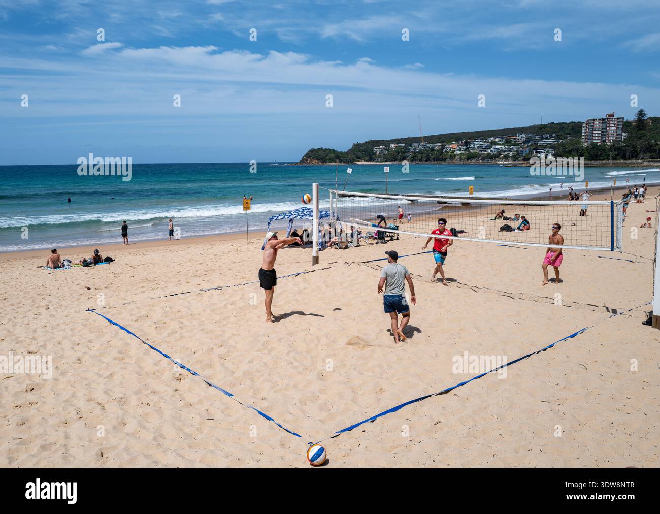 Action-Aufnahme eines Beachvolleyballspiels auf dem Sand mit dem Ball in der Luft am Manly Beach. Stockfoto