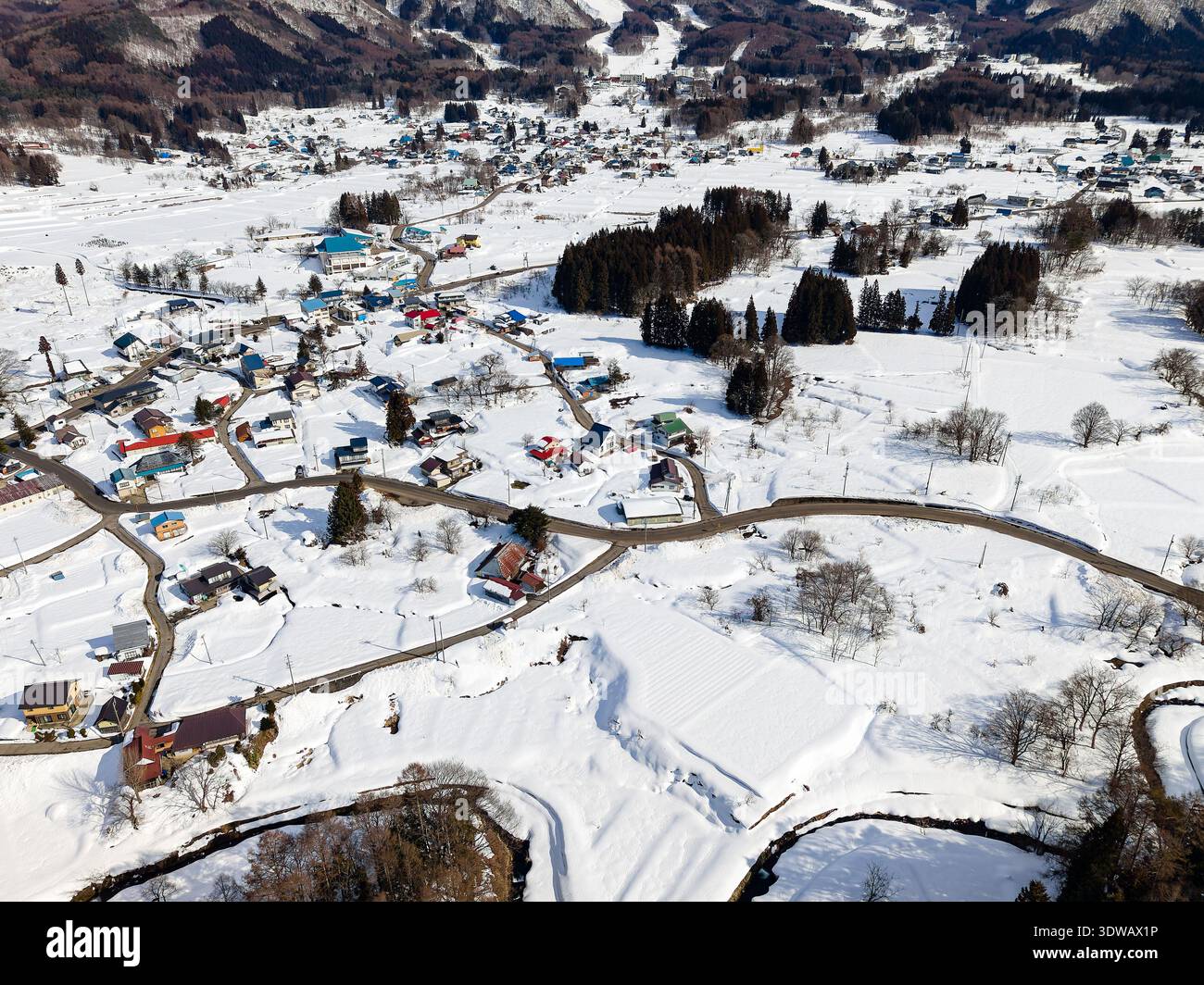 Sonnige Winterlandschaft in der Präfektur Nagano mit Häusern und schneebedeckten Feldern Stockfoto
