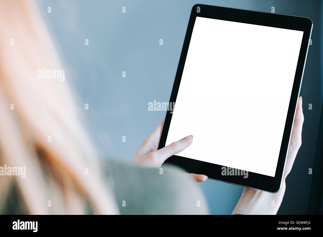 Nahaufnahme einer Frau, die ein Tablet mit leerem weißen Bildschirm in weichem natürlichem Licht hält. Saubere moderne Komposition mit Kopierraum, ideal für App-Mockups, d Stockfoto