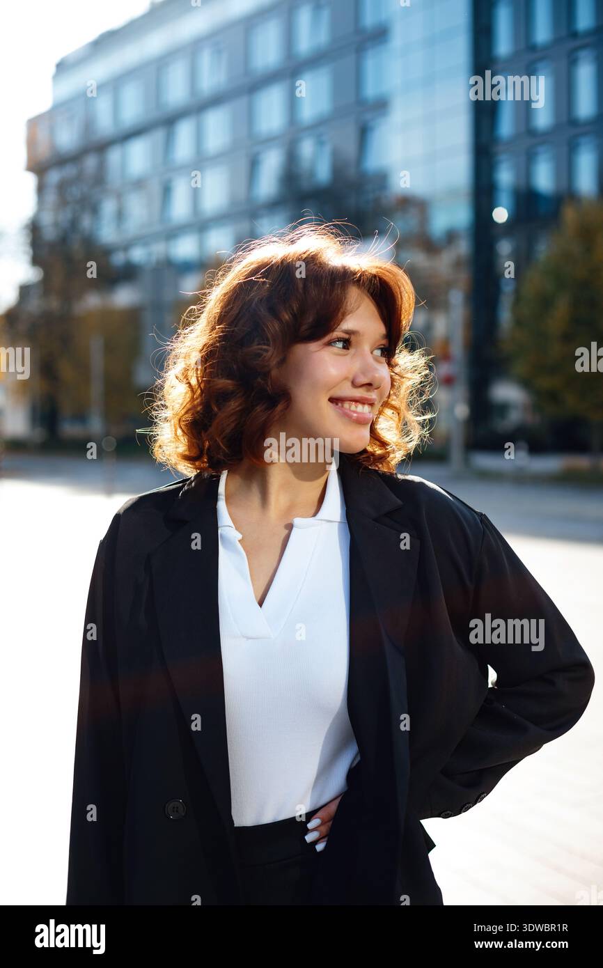 Professionelle Frau, die selbstbewusst mit starker Haltung im modernen Stadthintergrund steht. Stockfoto