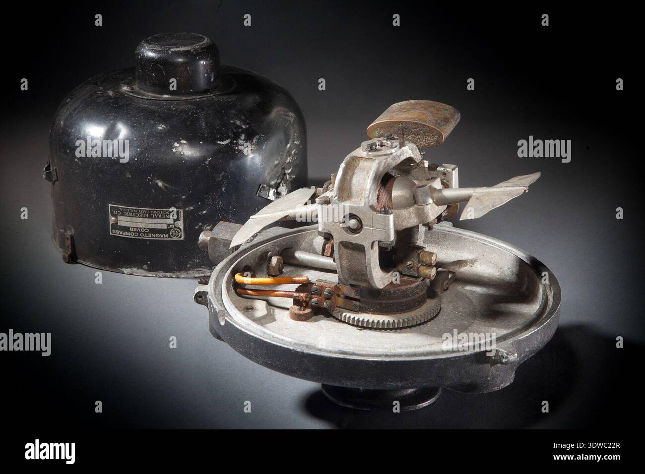 Generating Unit, Magneto Compass, Earth Inductor, war ein windbetriebener elektrischer Generator, der mit einem Kompasssystem für die Erdungsinduktivität eines Flugzeugs assoziiert war und als Modell 28A12A-1 identifiziert und als beschädigt beim Wiley Post-Unfall dokumentiert wurde. Das Archivbild zeichnet die Verformung des Gehäuses und die Befestigungsmerkmale der Windkraftanlage auf. Der historische Fotodruck dokumentiert das Generatorgehäuse und die Schlagschäden zur technischen Referenz. Stockfoto