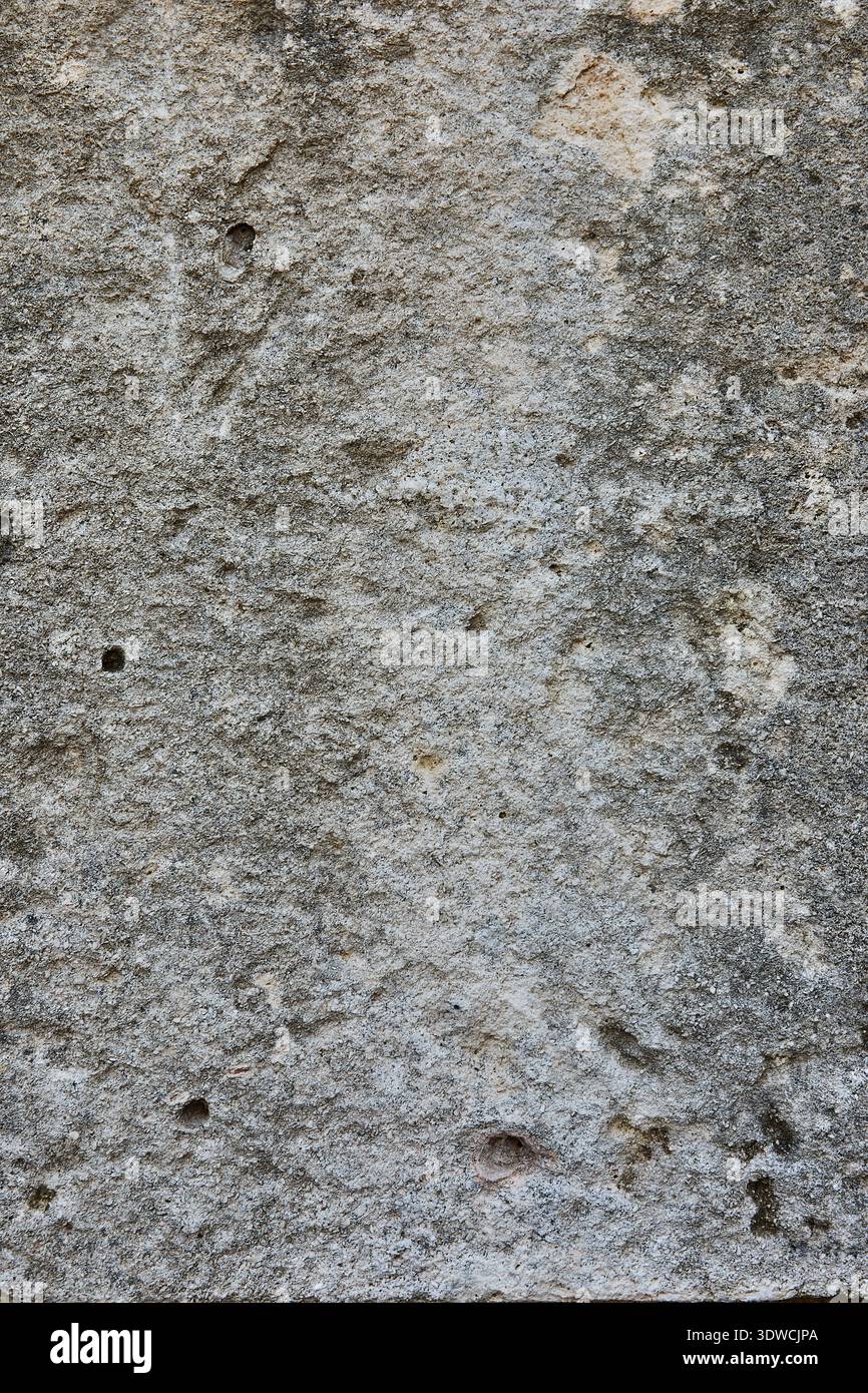 Strukturierte graue Steinoberfläche mit sichtbaren natürlichen Mustern und kleinen Löchern, geeignet für Hintergründe oder architektonische Designelemente in verschiedenen Ausführungen Stockfoto