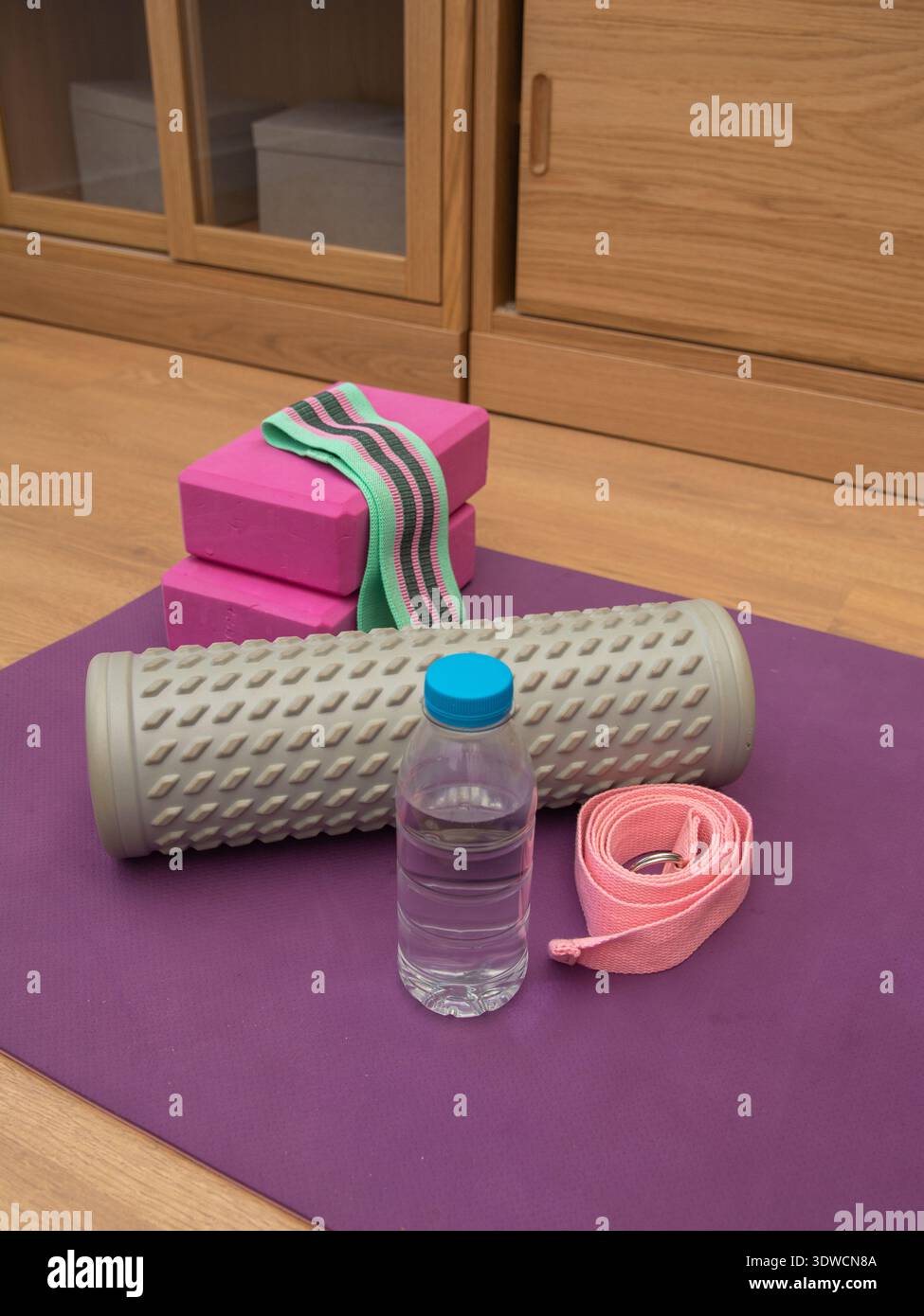 Sammlung von Fitnessgeräten zu Hause, einschließlich Yogamatte, Massagekugeln zur myofaszialen Entlastung, Schaumstoffrolle, Yogariemen, Widerstandsband und Wasserbock Stockfoto