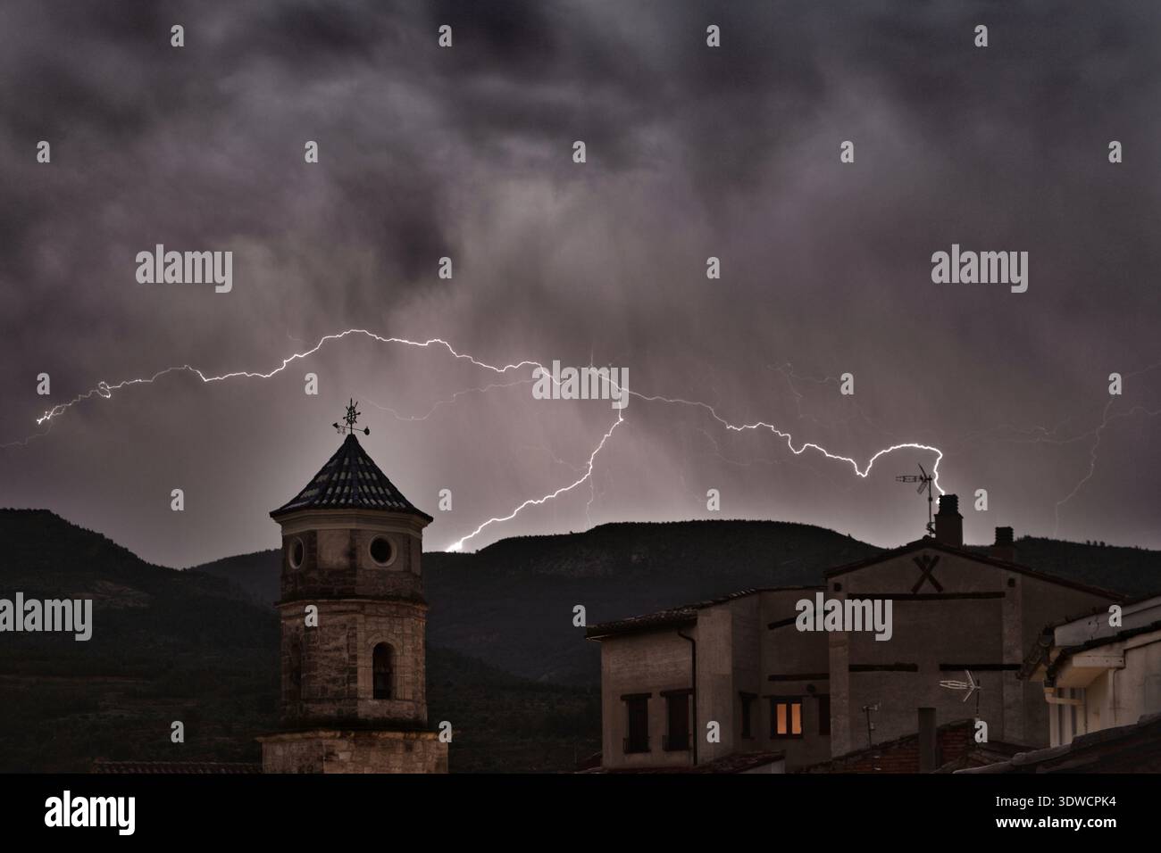 Blitze über einem dramatischen Nachthimmel über dem historischen Dorf Casas Altas in Valencia (Spanien) erleuchten einen Glockenturm und Dächer Agave Stockfoto