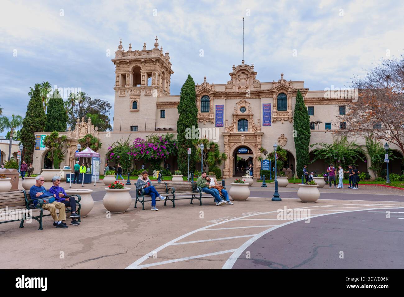 San Diego, Kalifornien - 31. Dezember 2025: Menschen entspannen sich auf Bänken vor der historischen Architektur des Prado im Balboa Park bei bewölktem Wetter Stockfoto