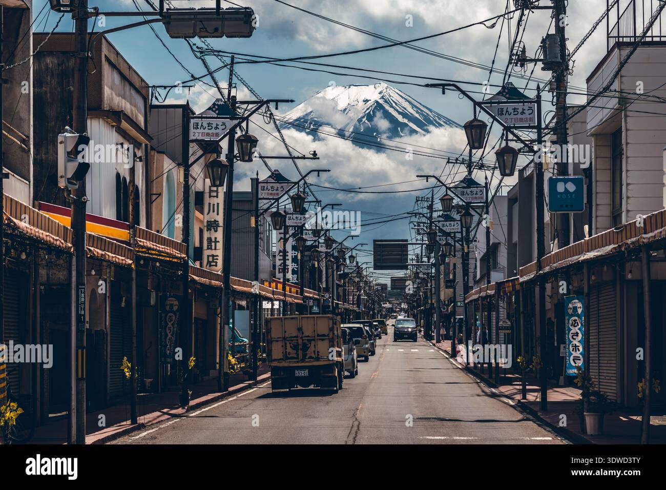 Fujiyoshida, Japan - 21. Mai 2023: Blick auf den majestätischen Berg Fuji, der mit Schnee bedeckt ist und sich über der Stadtstraße erhebt, eingerahmt von Gebäuden und komplizierten UW Stockfoto