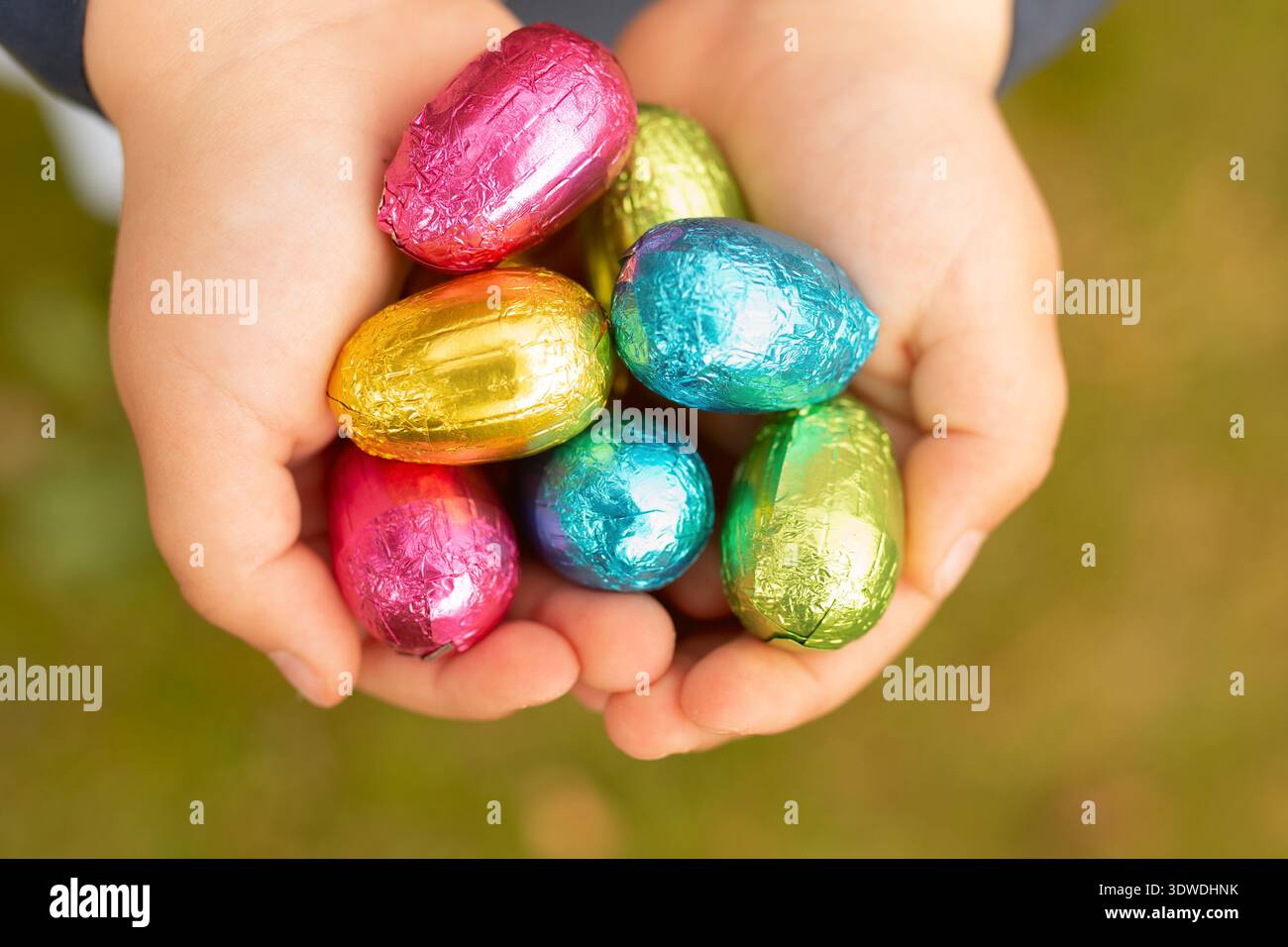 Schokoladeneier in Folie, Osterfarbenes Dekor. Eier in den Händen eines Kindes Ostereier. Stockfoto