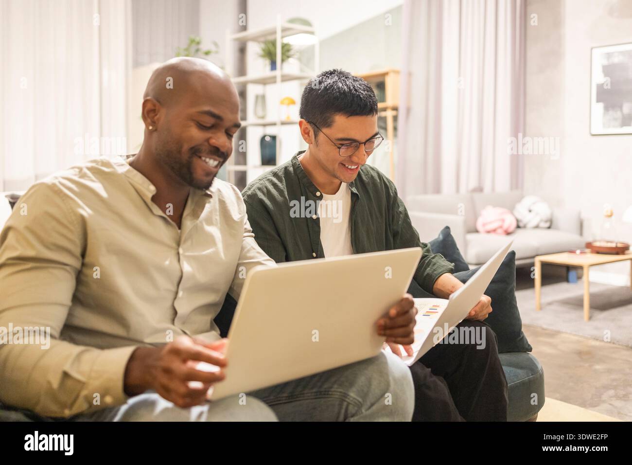 Zwei Kollegen, die Laptops in einem gemütlichen Coworking-Büro nutzen und an einem Projekt zusammenarbeiten. Die entspannte Umgebung fördert Kreativität und Teamarbeit, enhan Stockfoto