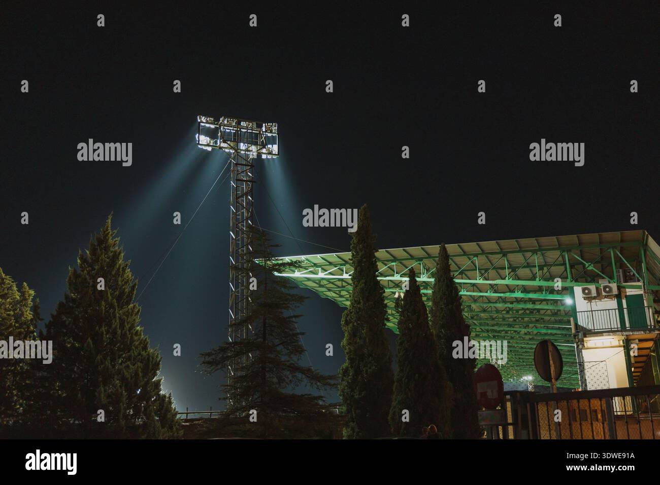 Ein Sportstadion wird bei Nacht durch leistungsstarke Flutlichter lebhaft beleuchtet, die Lichtstrahlen über das Feld werfen. Die energieeffiziente Beleuchtung enhan Stockfoto