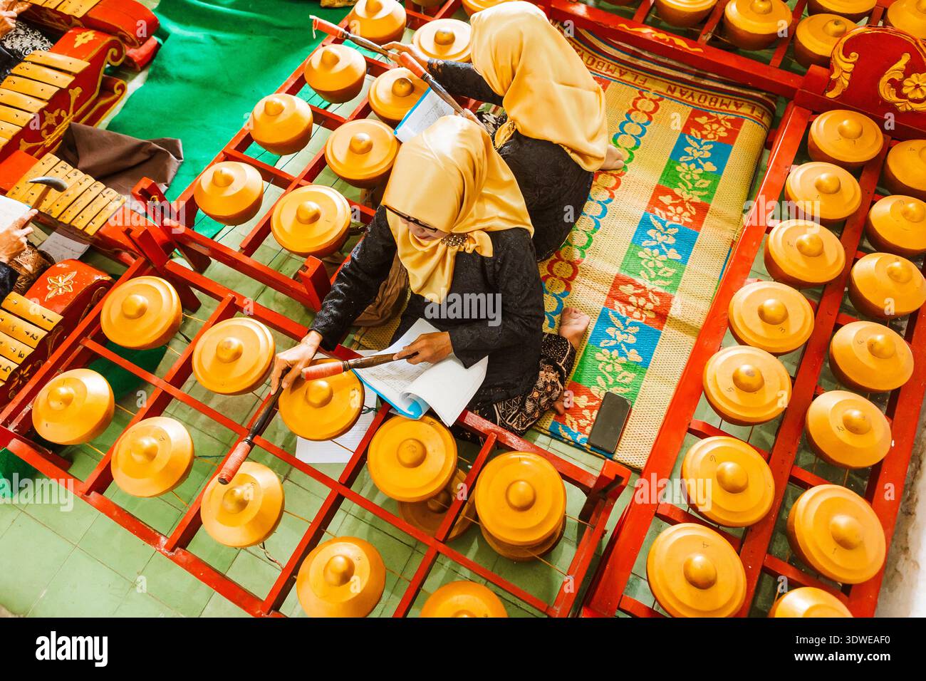 Zwei Musiker spielen ein traditionelles javanisches Gamelan-Ensemble, das Java mit komplizierten indonesischen Instrumenten und Reimen das reiche kulturelle Erbe darstellt Stockfoto