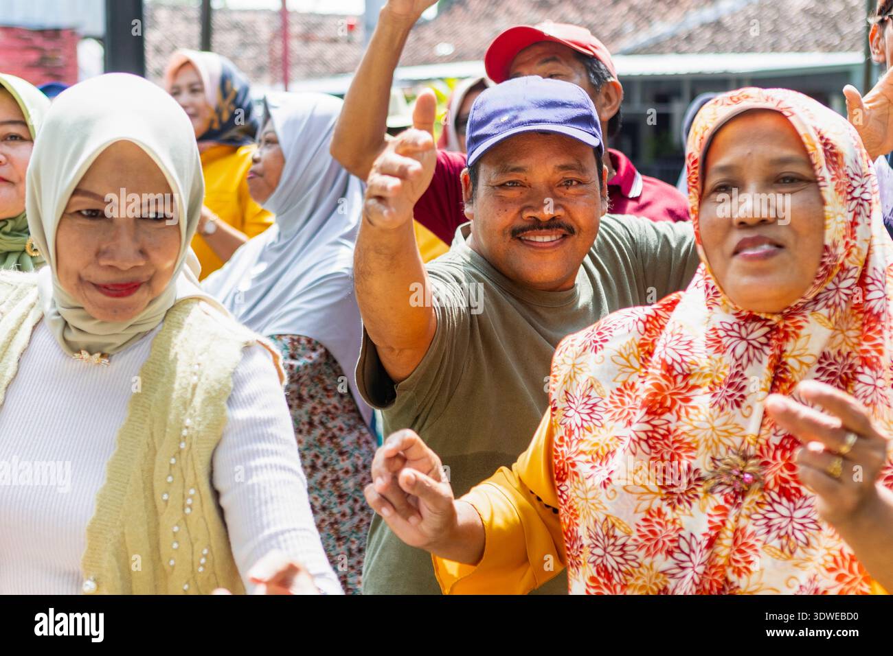 Eine lebhafte Straßenkaraoke-Szene in Indonesien fängt die Freude und das miteinander der Gemeinschaft ein. Die Leute singen und tanzen draußen und schaffen ein lebendiges und Stockfoto