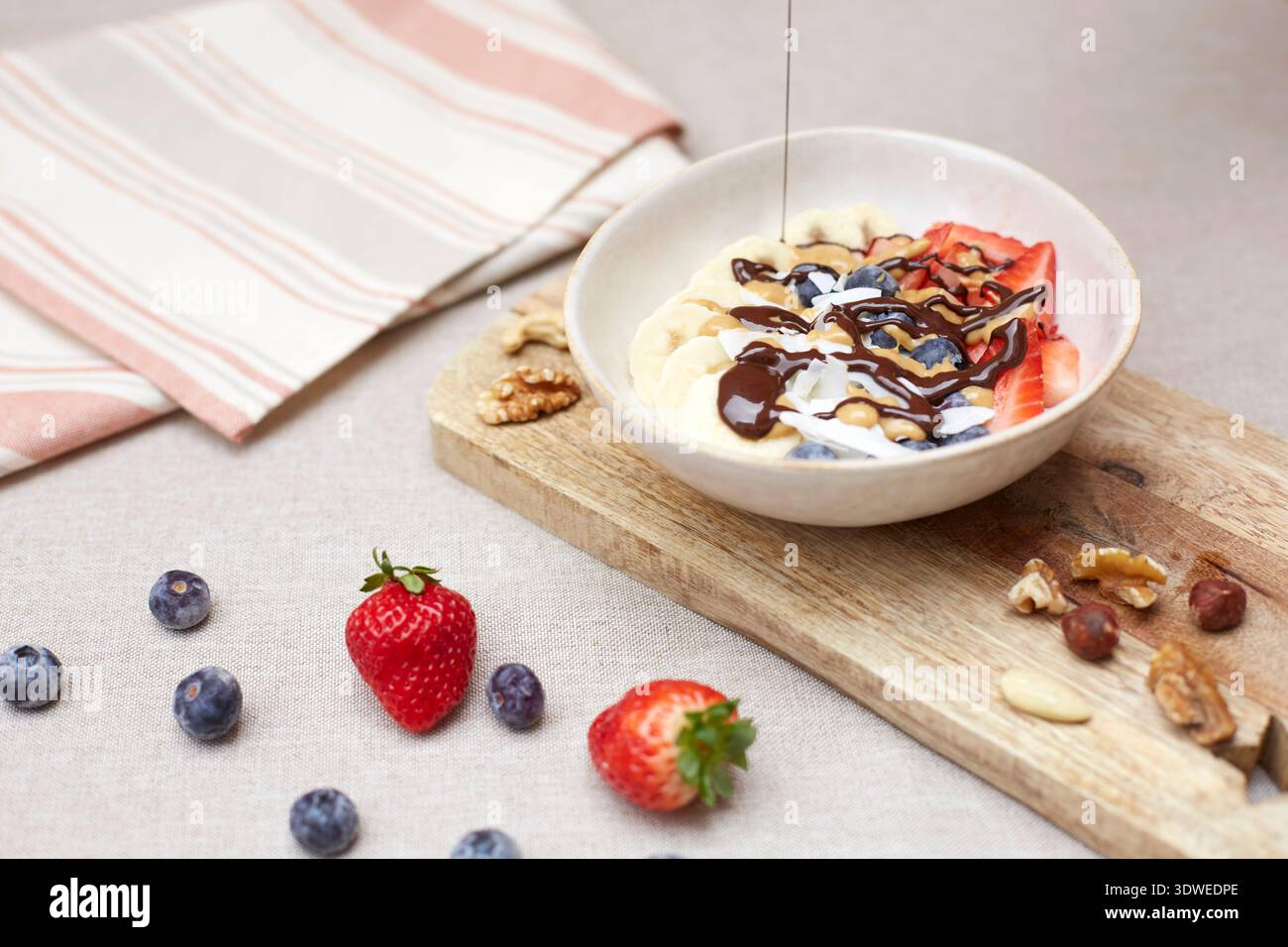 Eine köstliche und nahrhafte Frühstücksschale mit frischen Erdbeeren, Bananen und Heidelbeeren, getränkt mit Schokolade, perfekt für den Start in Ihr d Stockfoto