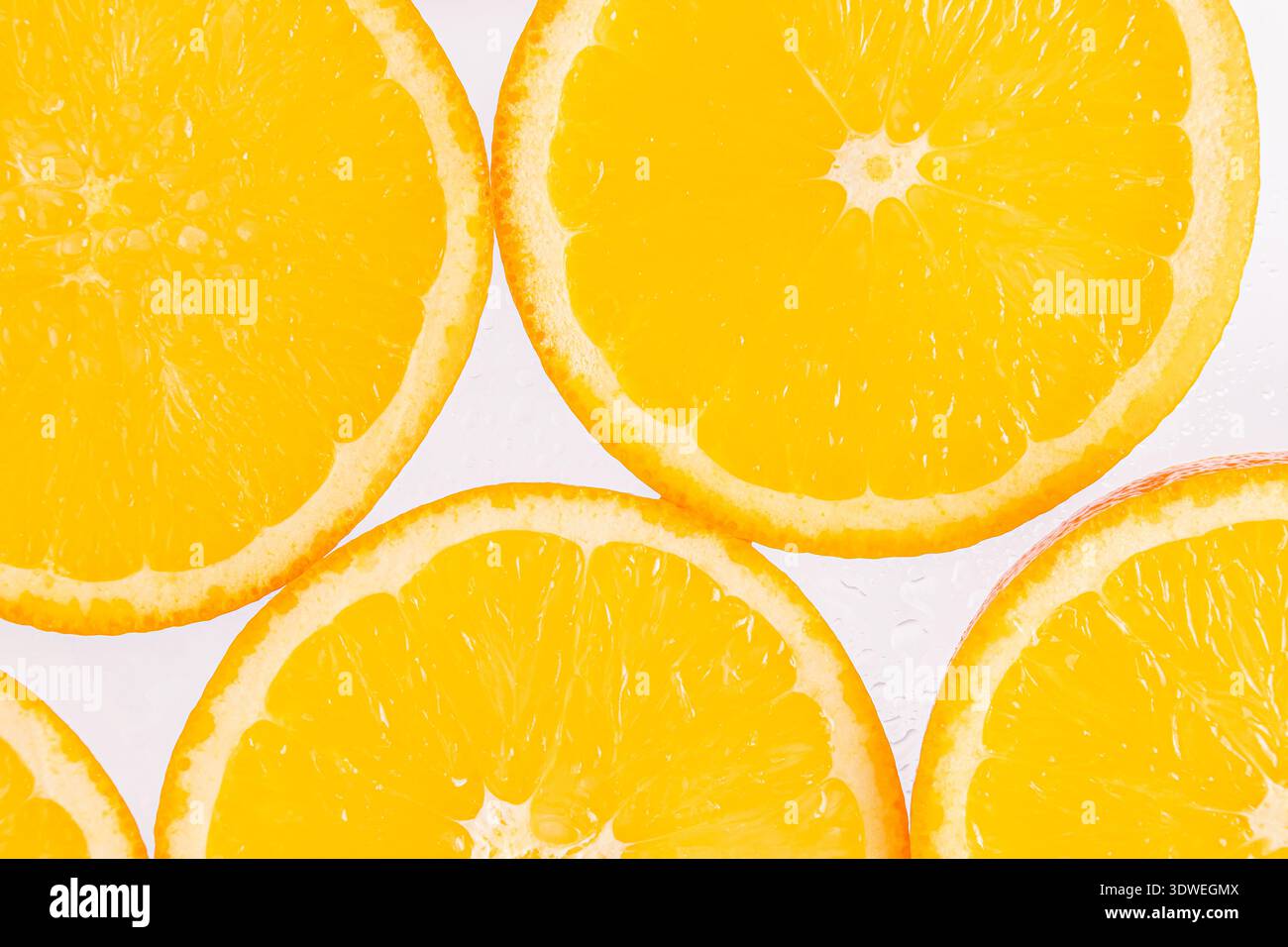Leuchtende orangefarbene Scheiben auf einem sauberen, weißen Hintergrund, die ihre Frische zum Ausdruck bringen. Diese Früchte sind reich an Vitamin C und eignen sich hervorragend für eine erfrischende Stockfoto