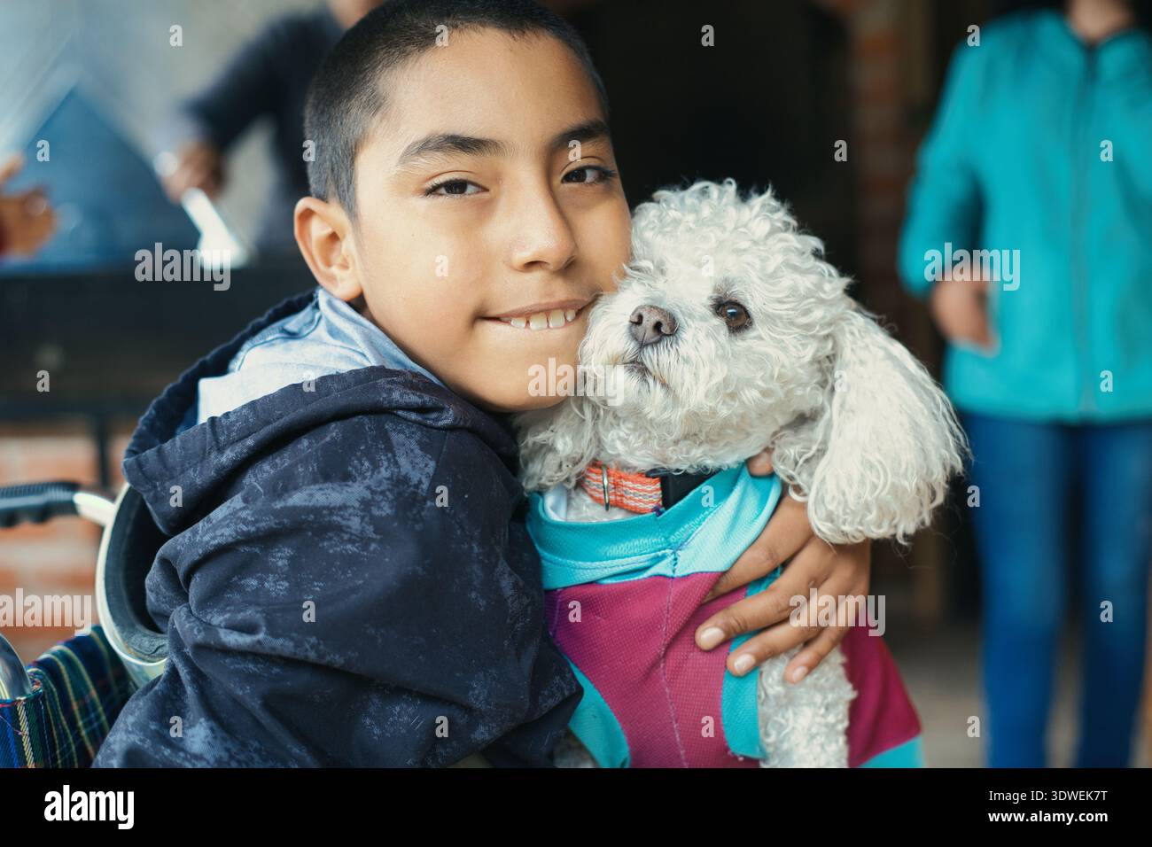 Porträt eines lächelnden behinderten Kindes, das seinen flauschigen weißen Therapiehund umarmt, um den integrativen Tourismus zu fördern und die positiven Auswirkungen von Haustieren auf das Thema zu verdeutlichen Stockfoto