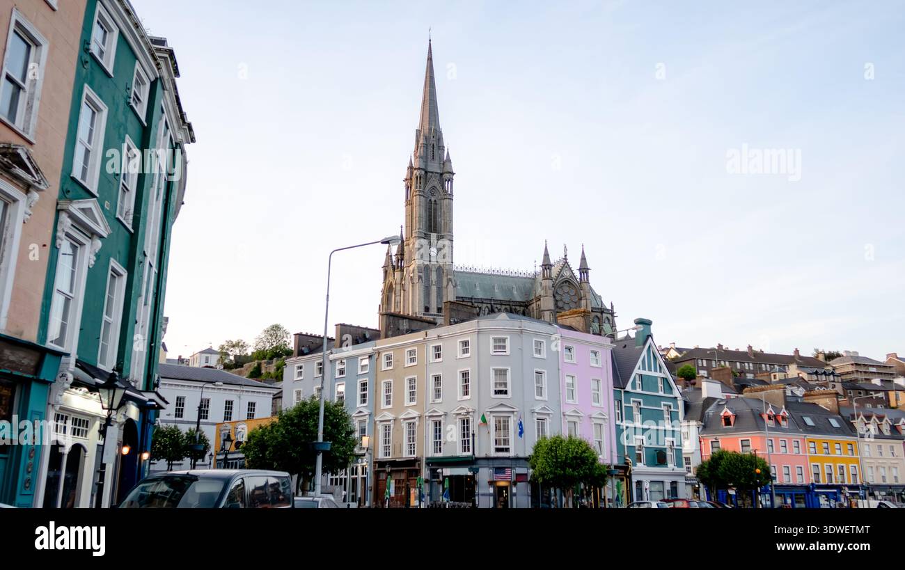 Ein atemberaubender Blick auf die St. Colman's Cathedral in Cobh, Irland, von den lebhaften, mehrfarbigen Häusern in den unteren Straßen der Stadt an einem ruhigen Tag aus gesehen. Stockfoto