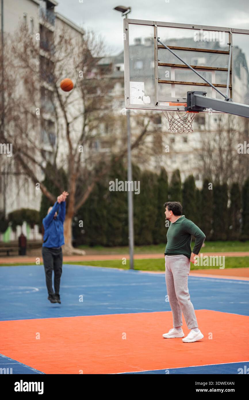 Männer spielen Basketballspiel auf dem Platz im Freien Stockfoto