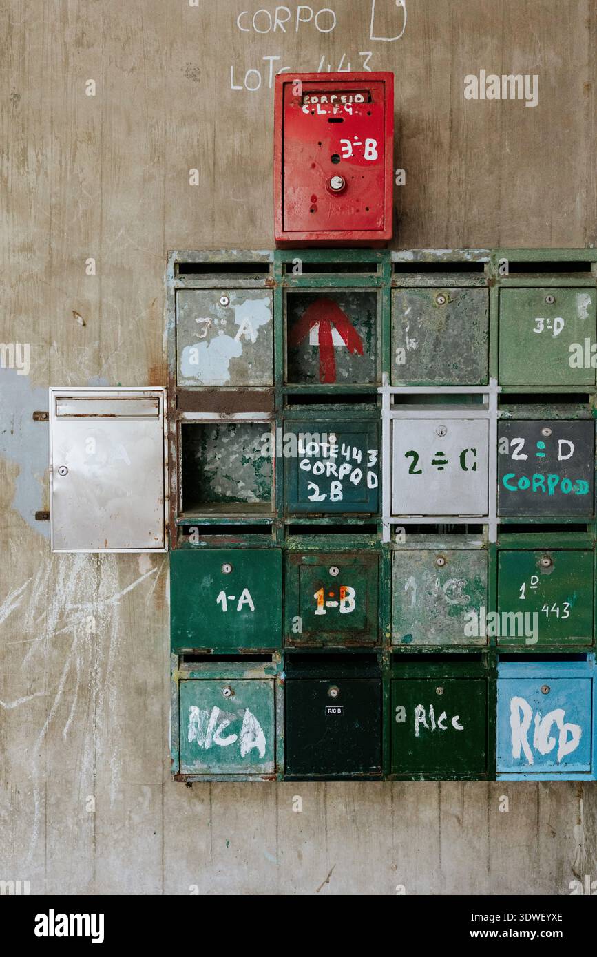 Eine Sammlung verwitterter Briefkästen, die mit farbenfrohen Graffiti und Schildern verziert sind, befindet sich vor einer rustikalen Wand und zeigt einen urbanen künstlerischen Ausdruck Stockfoto