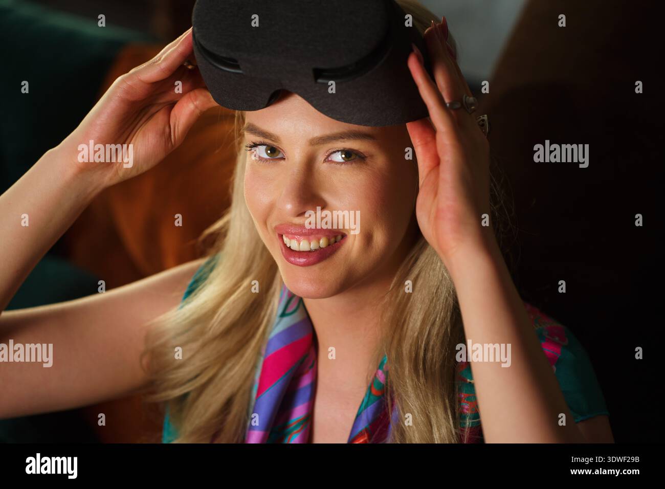 Eine blonde Frau mit einem fröhlichen Ausdruck benutzt ein Virtual-Reality-Gadget. Sie ist in ein digitales Erlebnis eingetaucht und zeigt die Spannung und das Potential Stockfoto