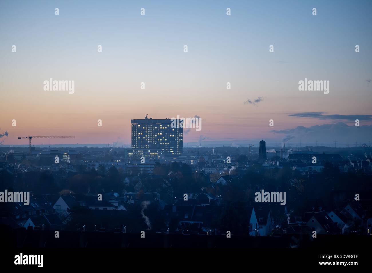 Beschreibung: Skyline der Stadt Köln bei Sonnenaufgang mit großen leuchtenden Stadtgebäuden und einem Abendhimmel. Stockfoto