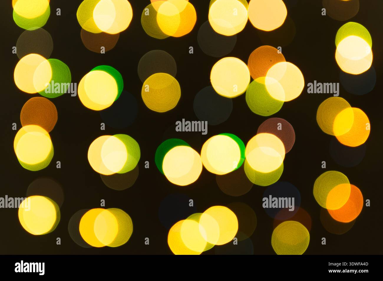 Verschwommene Lichter einer Girlande aus grünen, orangen, gelben, roten Farben. Weihnachtliche Texturen für Dekoration und grafisches Design. Stockfoto