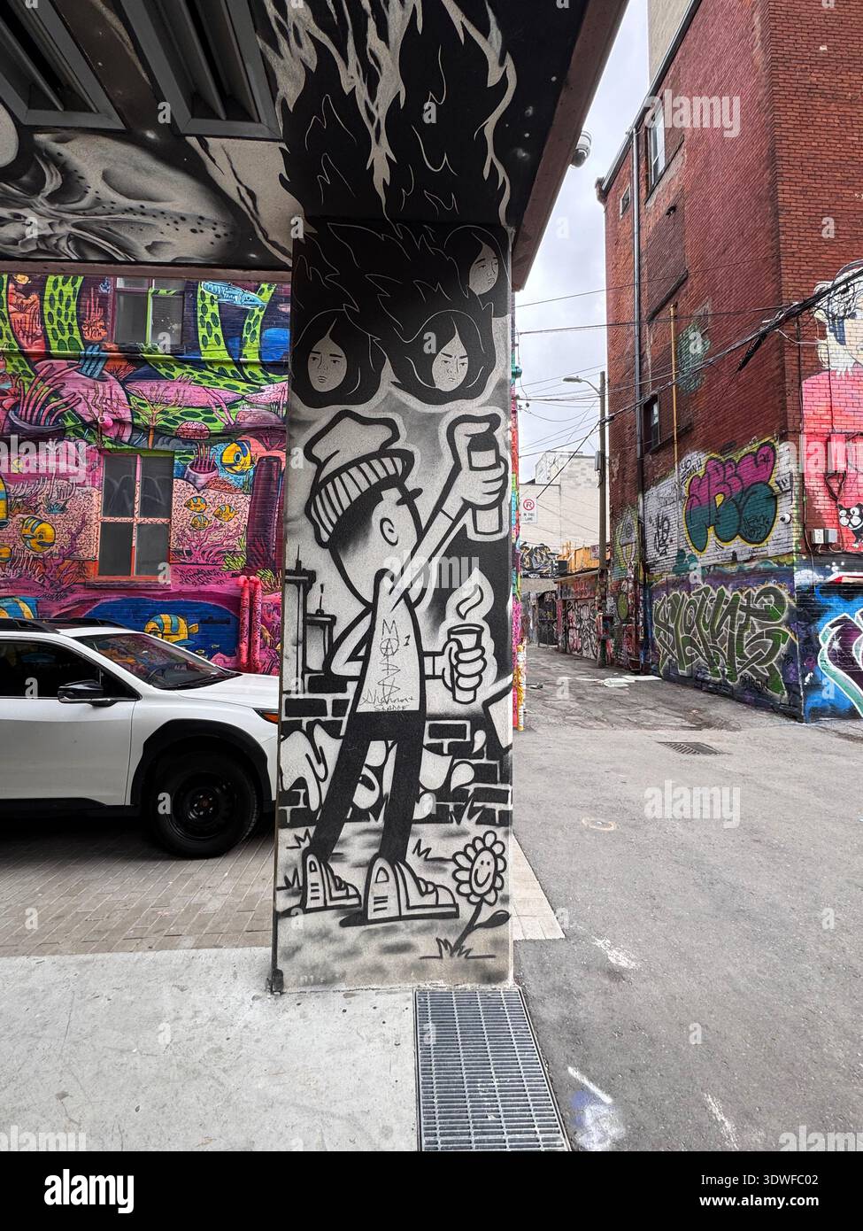 Street Art Wandgemälde auf einer Betonsäule in der Graffiti Alley, Toronto, Ontario, Kanada, mit farbenfrohen Graffiti-bedeckten Gebäuden im Hintergrund. - Smartphone-aufgenommenes Stockfoto