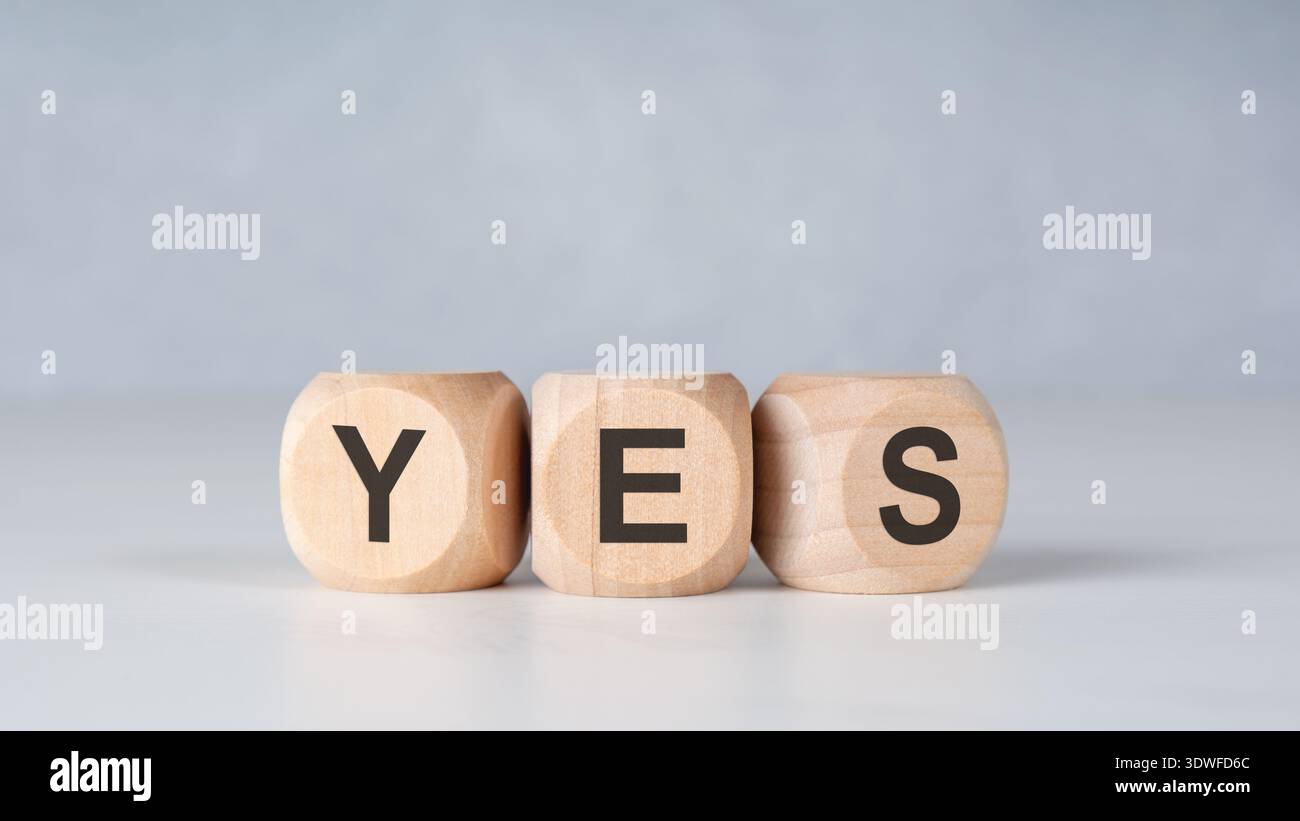 Vorderansicht von Holzblöcken mit der Schreibweise JA auf einer hellgrauen Oberfläche. Minimalistisches Konzept mit Kopierraum darüber. Stockfoto
