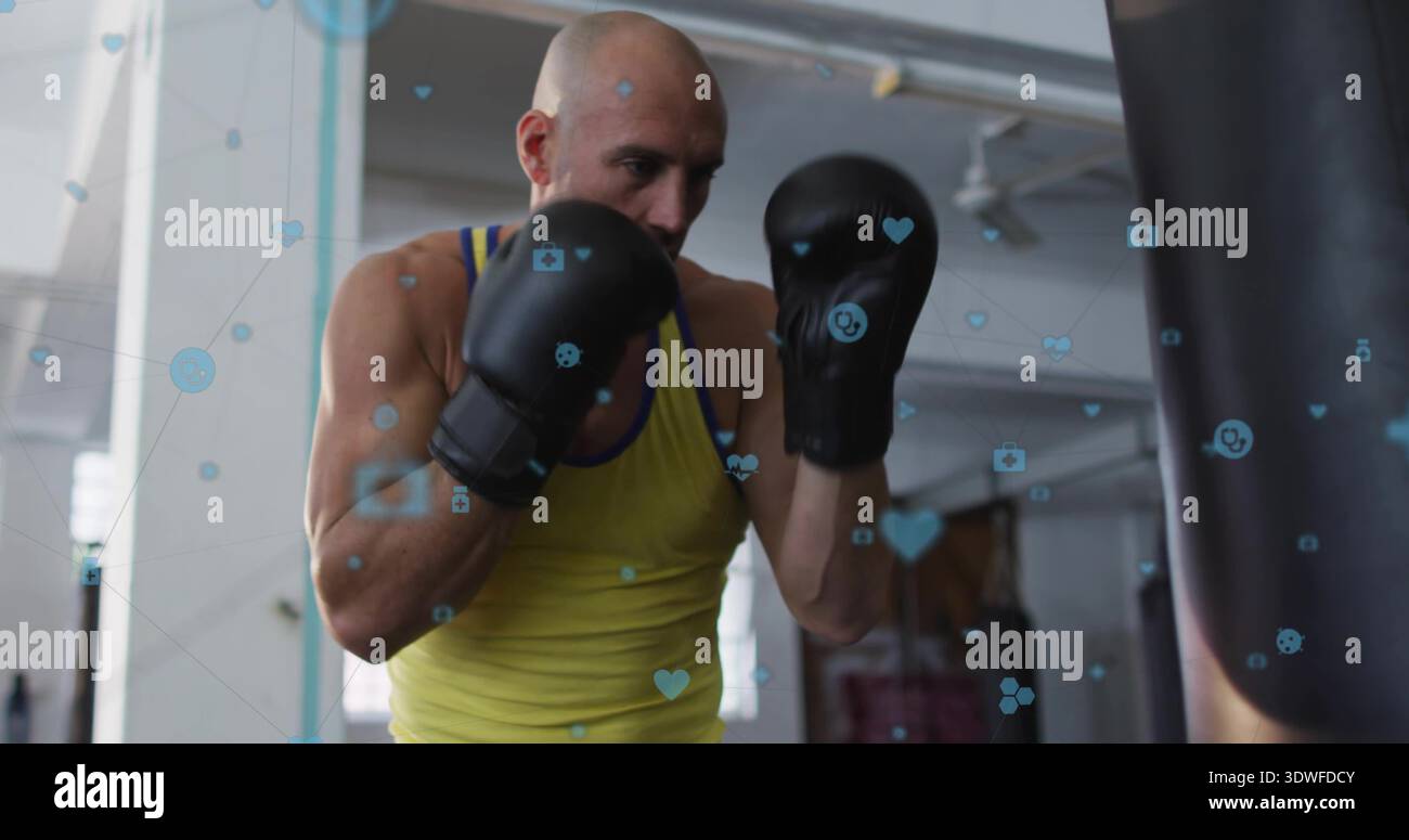 Trainingsboxer mit gelbem Tank und schwarzen Handschuhen, schwerer Tasche im Fitnessstudio, blaue Überzüge Stockfoto