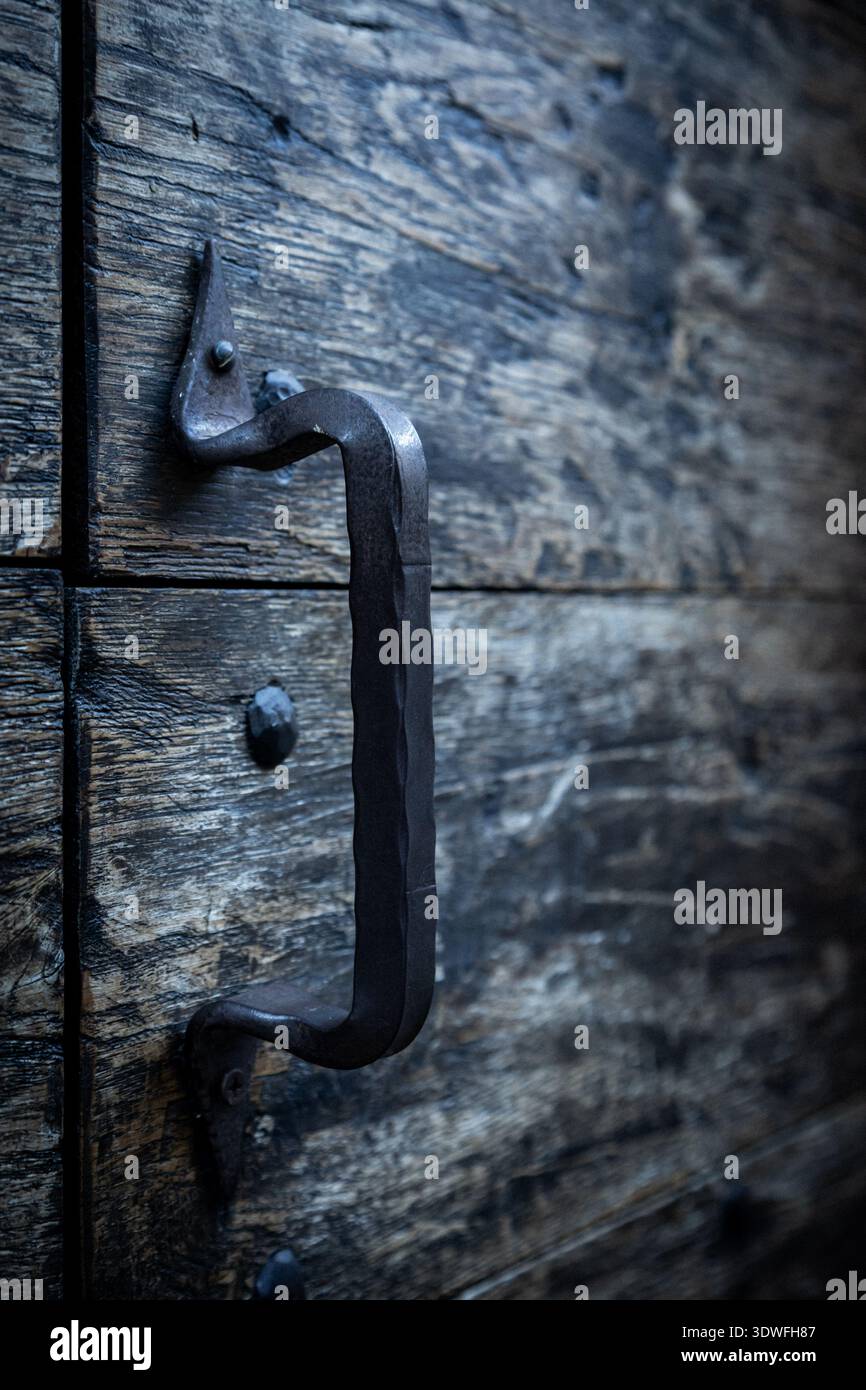 Nahaufnahme einer verwitterten Holztür mit geschmiedetem Eisengriff. Das Bild zeigt rustikale Handwerkskunst und veraltete Textur, die Geschichte, Einfachheit, A vermittelt Stockfoto