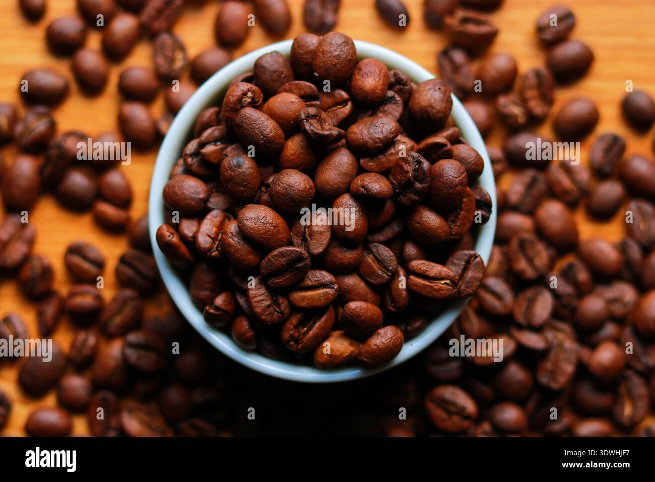 Kaffeebohnen in einer Schüssel auf hölzernem Hintergrund. Bild von oben Stockfoto