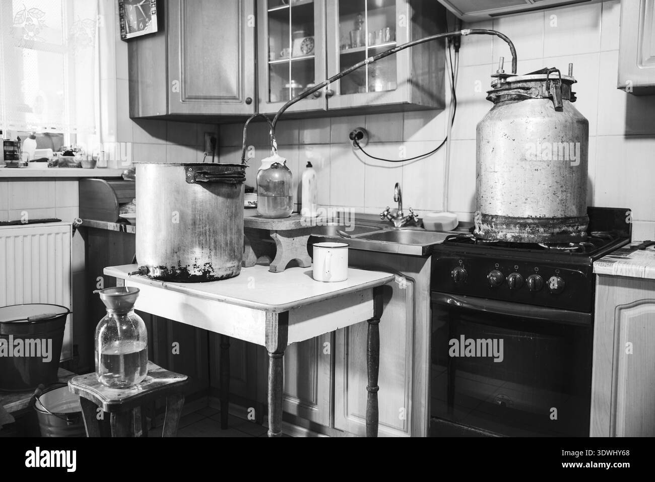 Altmodische Moonshine-Maschine zur Herstellung von hausgemachtem, starkem Alkohol in der Küche. Prozess der Destillation, allgemeine Ansicht. Geschichte über eine gealterte Art von Stockfoto
