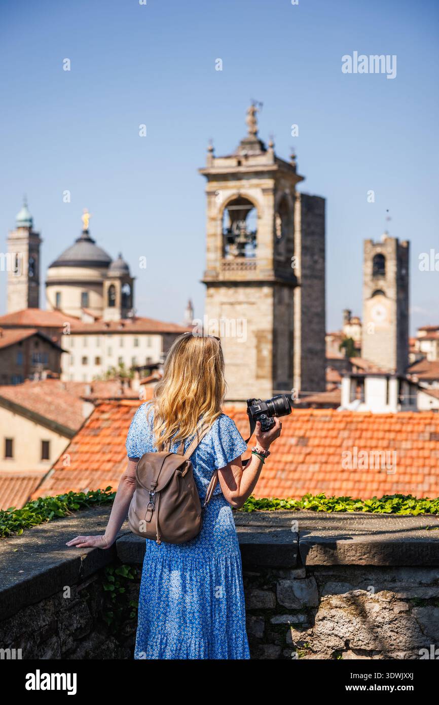 Frau Touristen fotografiert auf Kamera Stadt Skyline in Citta Alta, Bergamo, Italien während Städtereise Urlaub. Alleinreiseurlaub in Europa Stockfoto