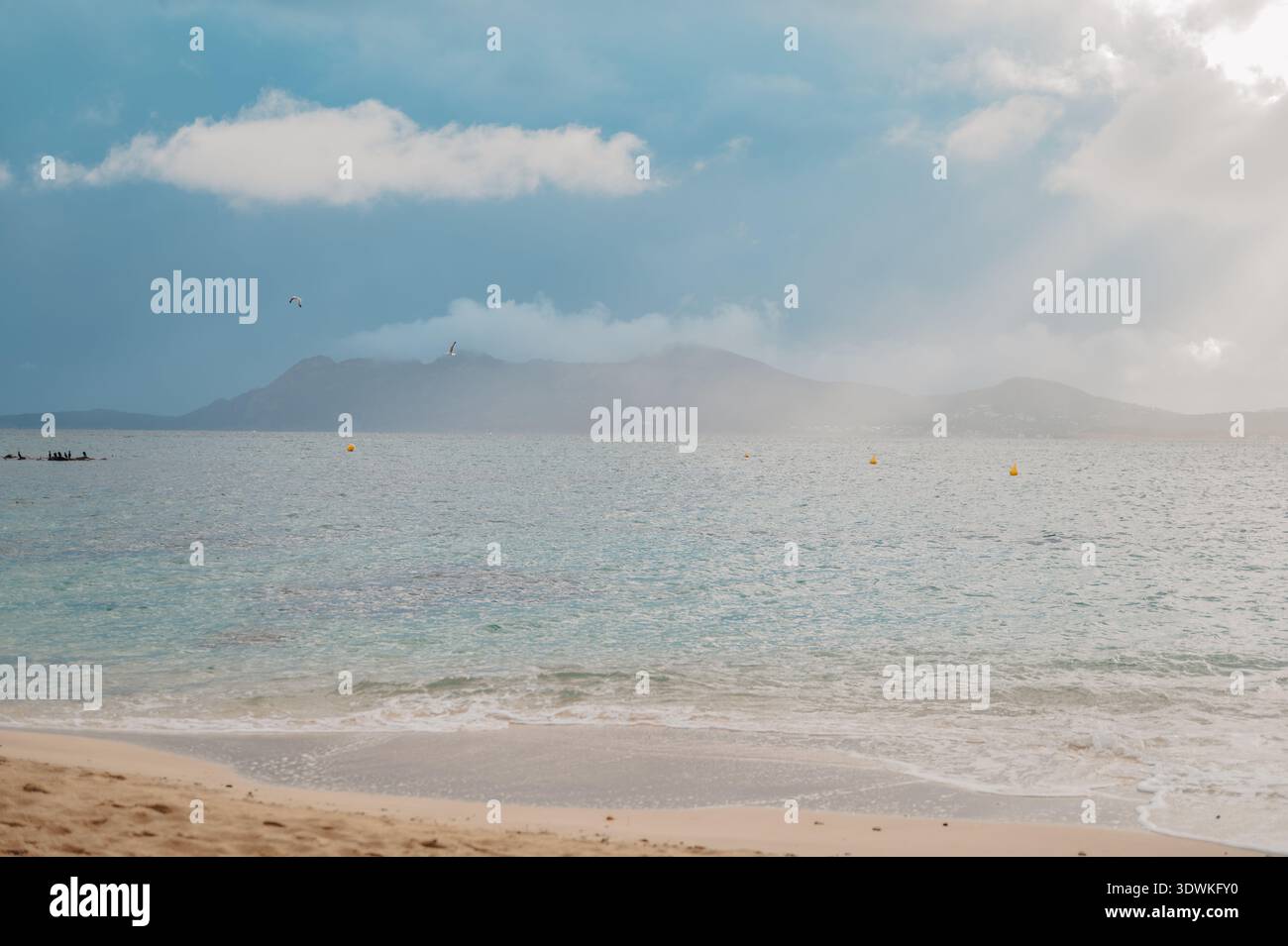 Sonnendurchflutetes Meer mit fernen Bergen und sanften Wellen am Port de Pollenca Stockfoto