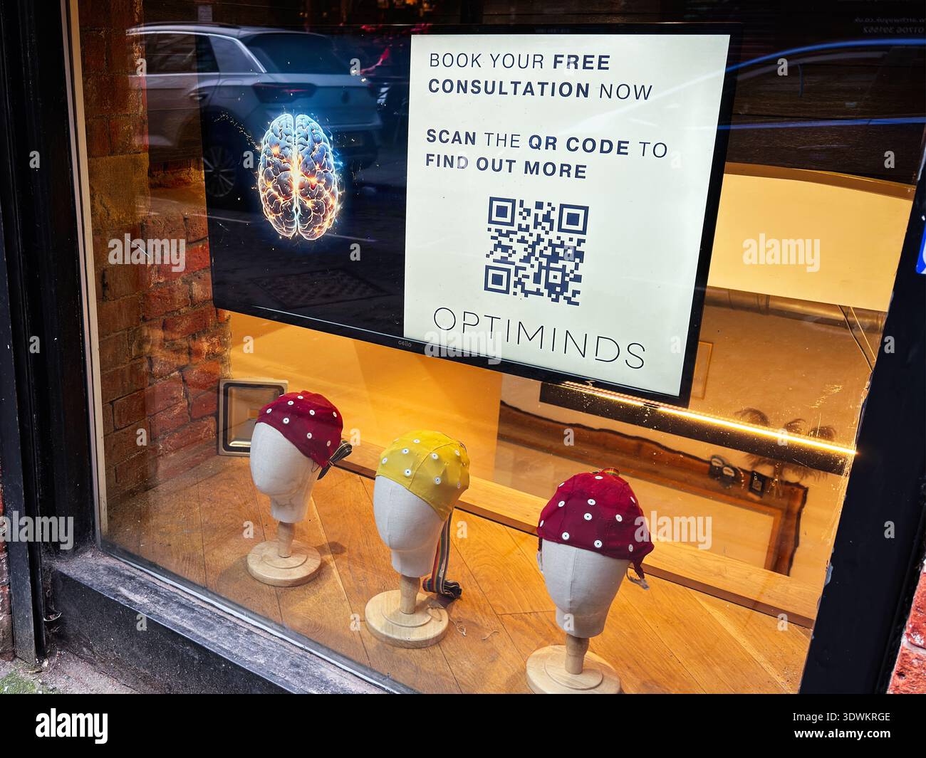 Manchester, Großbritannien - 30. Januar 2026: Werbebild in einem Schaufenster von Manchester Optiminds mit Hüten auf Schaufensterpuppen und einem QR-Code. Stockfoto