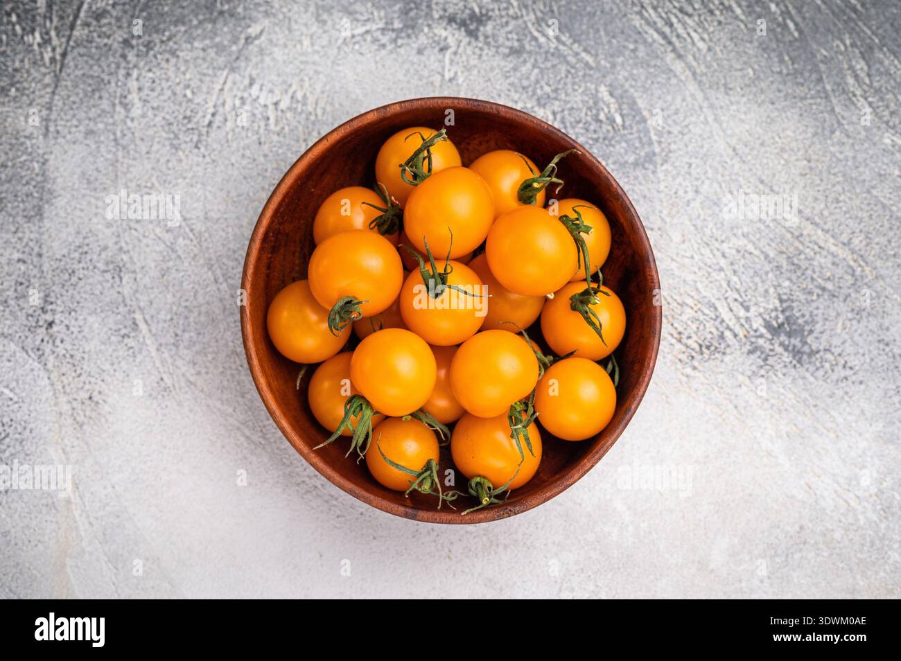 Frische kleine gelbe Kirschtomaten-Sortiment, Mini-Bio-Cocktail-Tomatenmischung. Grauer Hintergrund. Draufsicht. Stockfoto