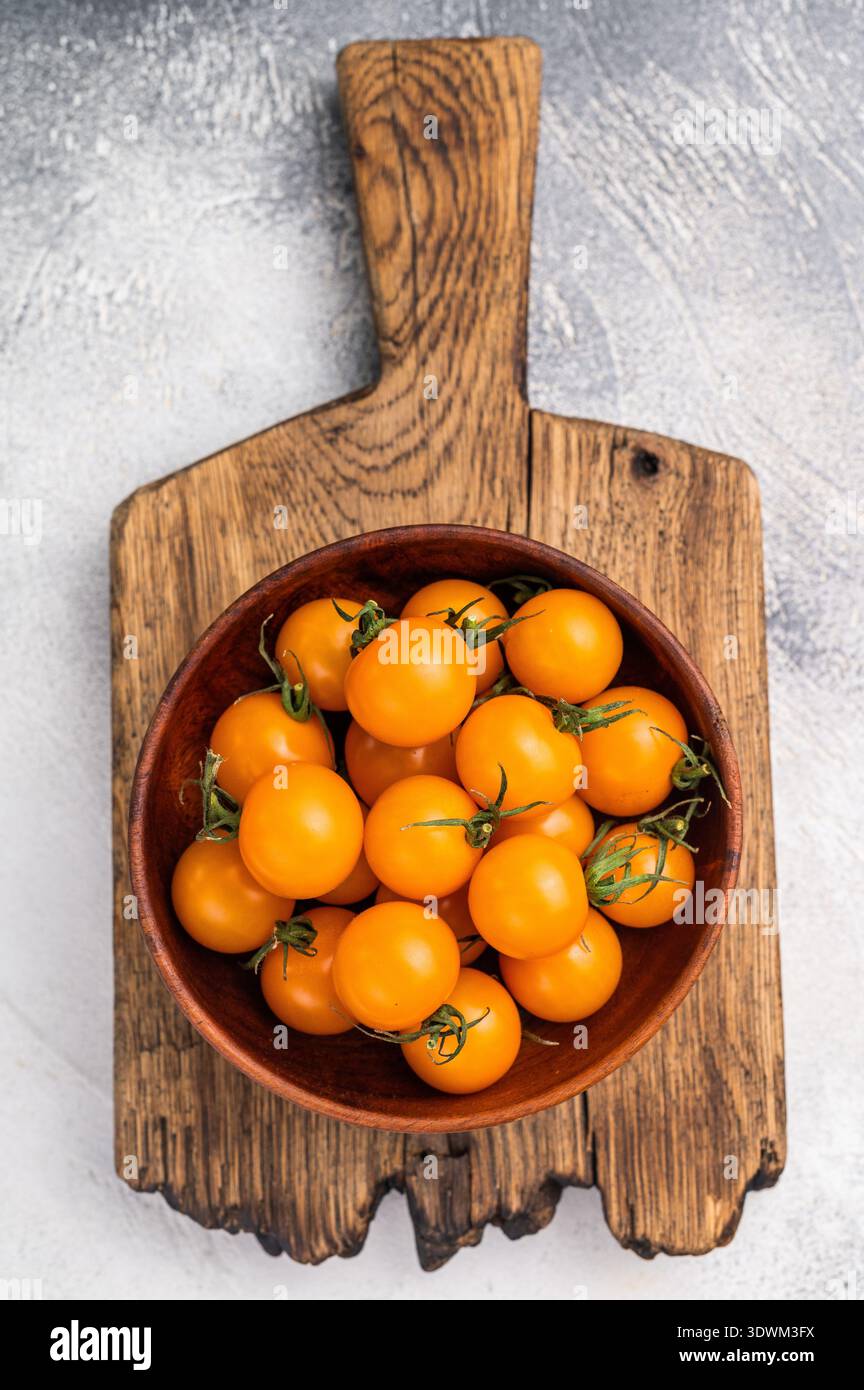 Frische kleine gelbe Kirschtomaten-Sortiment, Mini-Bio-Cocktail-Tomatenmischung. Grauer Hintergrund. Draufsicht. Stockfoto