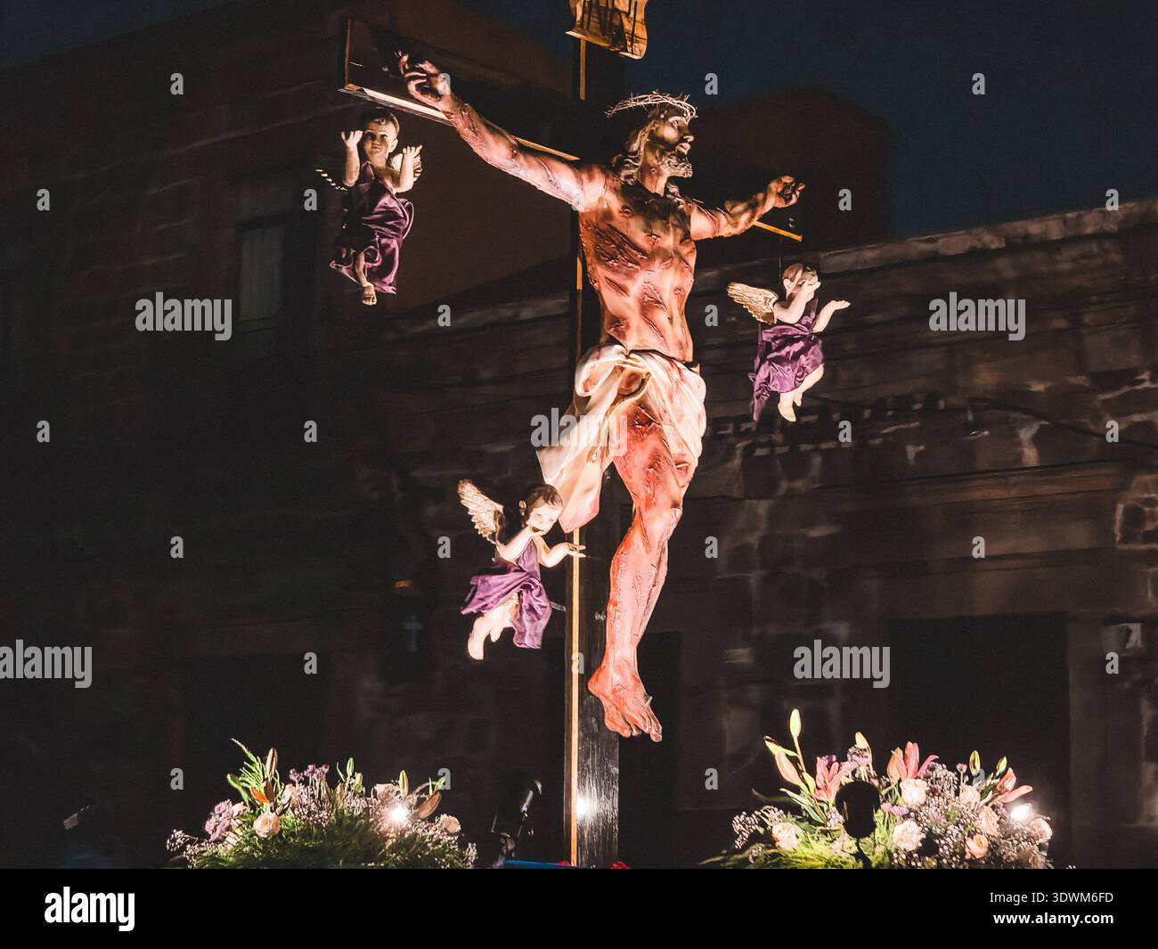Eine Kreuzigungsszene mit einem Mann und zwei Engeln. Der Mann ist mit Blut bedeckt und die Engel halten Blumen Stockfoto