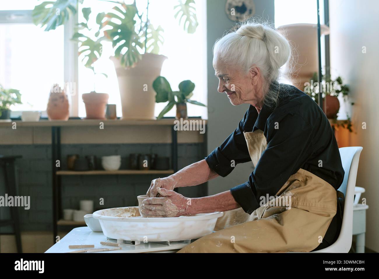 Senior Frau formt Tontopf auf Keramikrad im Kunststudio Stockfoto
