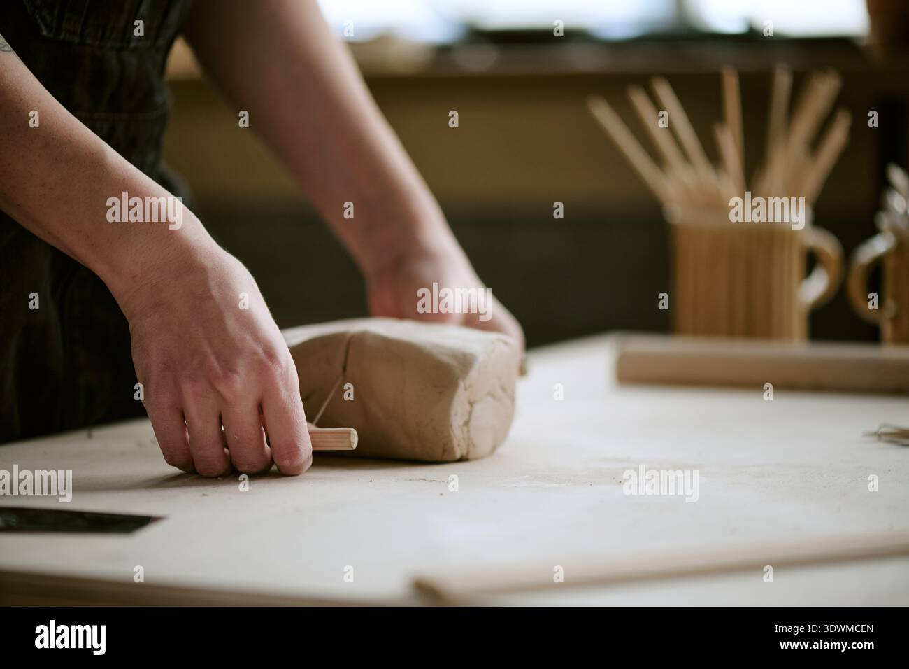 Frau formt Ton mit Holzwerkzeug im Töpferstudio Stockfoto