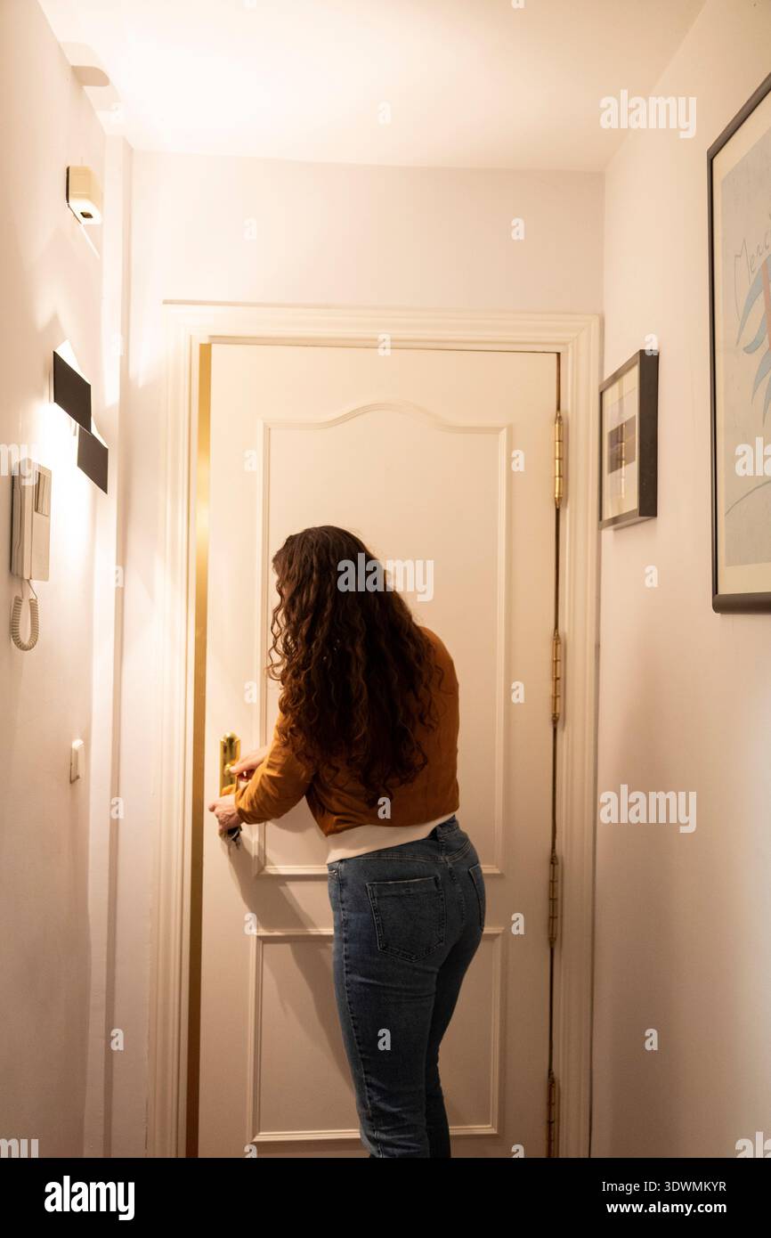 Frau, die eine Wohnungstür mit einem Schlüssel öffnet, in ihr Haus eingeht oder verlässt Stockfoto