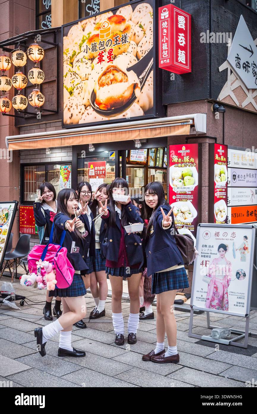 Japan, Honshu Island, Tokio, Asakusa District, Schulmädchen in Uniform essen auf der Straße einen Imbiss Stockfoto